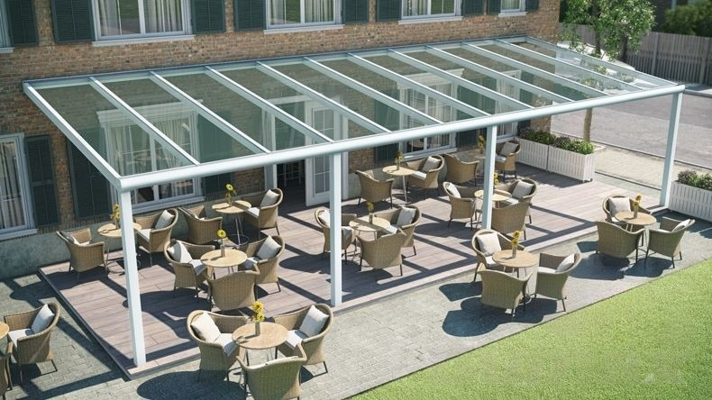 Vista dall'alto di una Veranda moderna bianco 9016, dimensioni 11,06 x 4,0 metri con tetto in vetro trasparente. Pergola/Gazebo elegante e resistente alle intemperie, ideale per spazi esterni raffinati e confortevoli, offre protezione UV ed è facile da montare.