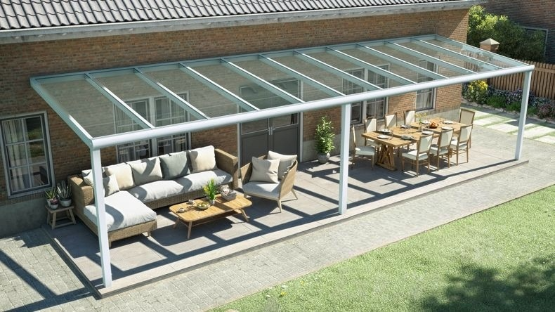Vista dall'alto di una Veranda moderna bianco 9016, dimensioni 12,06 x 3,0 metri con tetto in vetro trasparente. Pergola/Gazebo elegante e resistente alle intemperie, ideale per spazi esterni raffinati e confortevoli, offre protezione UV ed è facile da montare.