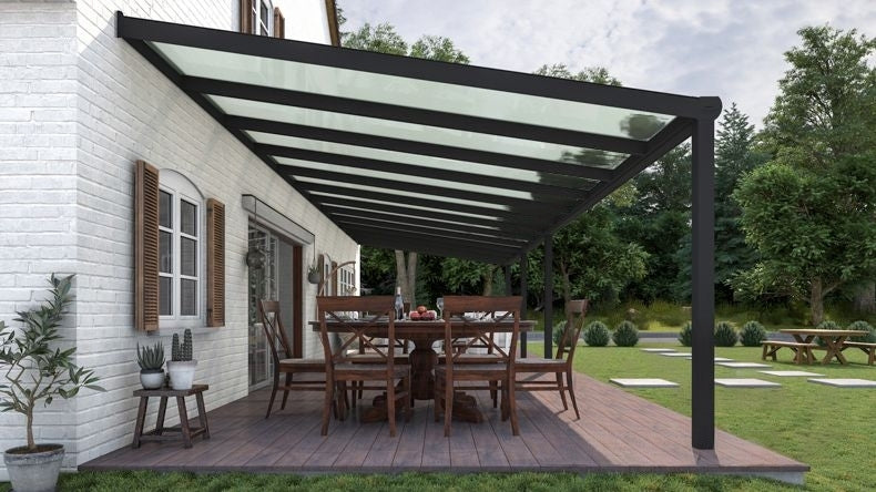Vista laterale di una Veranda moderna nero 9005, dimensioni 12,06 x 4,0 metri con tetto in vetro opale. Pergola/Gazebo elegante e resistente alle intemperie, ideale per spazi esterni raffinati e confortevoli, offre protezione UV ed è facile da montare.