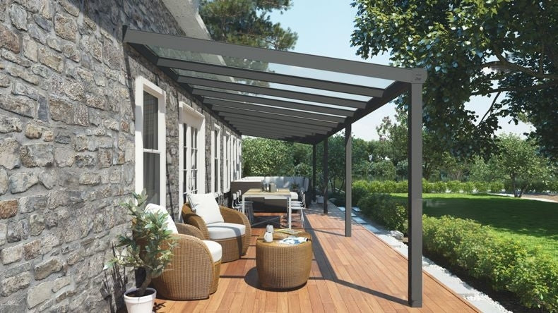 Vista laterale di una Veranda moderna antracite 7016, dimensioni 12,06 x 2,5 metri con tetto in vetro trasparente. Pergola/Gazebo elegante e resistente alle intemperie, ideale per spazi esterni raffinati e confortevoli, offre protezione UV ed è facile da montare.