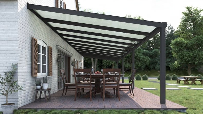 Vista laterale di una Veranda moderna antracite 7016, dimensioni 12,06 x 3,5 metri con tetto in vetro opale. Pergola/Gazebo elegante e resistente alle intemperie, ideale per spazi esterni raffinati e confortevoli, offre protezione UV ed è facile da montare.