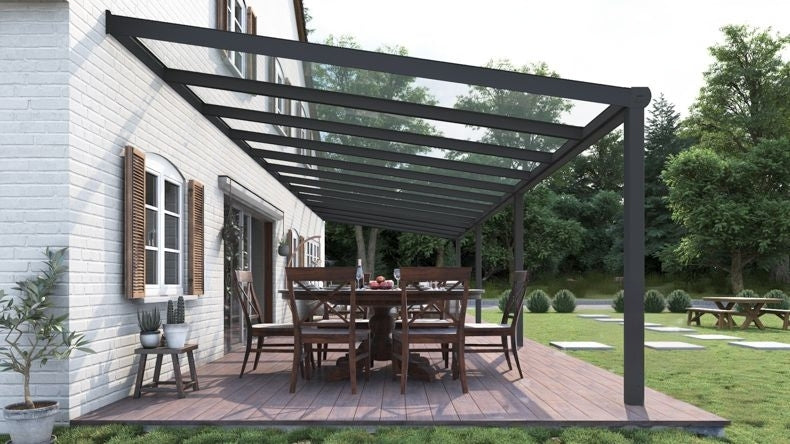 Vista laterale di una Veranda moderna antracite 7016, dimensioni 12,06 x 3,5 metri con tetto in vetro trasparente. Pergola/Gazebo elegante e resistente alle intemperie, ideale per spazi esterni raffinati e confortevoli, offre protezione UV ed è facile da montare.