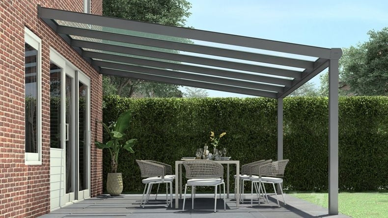 Vista laterale di una Veranda moderna antracite 7016, dimensioni 5,06 x 3,5 metri con tetto in vetro trasparente. Pergola/Gazebo elegante e resistente alle intemperie, ideale per spazi esterni raffinati e confortevoli, offre protezione UV ed è facile da montare.