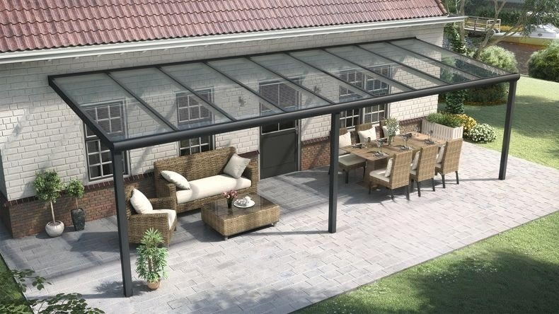 Vista laterale di una Veranda moderna nero 9005, dimensioni 10,06 x 2,5 metri con tetto in vetro trasparente. Pergola/Gazebo elegante e resistente alle intemperie, ideale per spazi esterni raffinati e confortevoli, offre protezione UV ed è facile da montare.